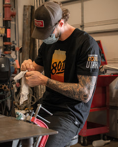 A person doing work in a workshop wearing a graphic print t-shirt.