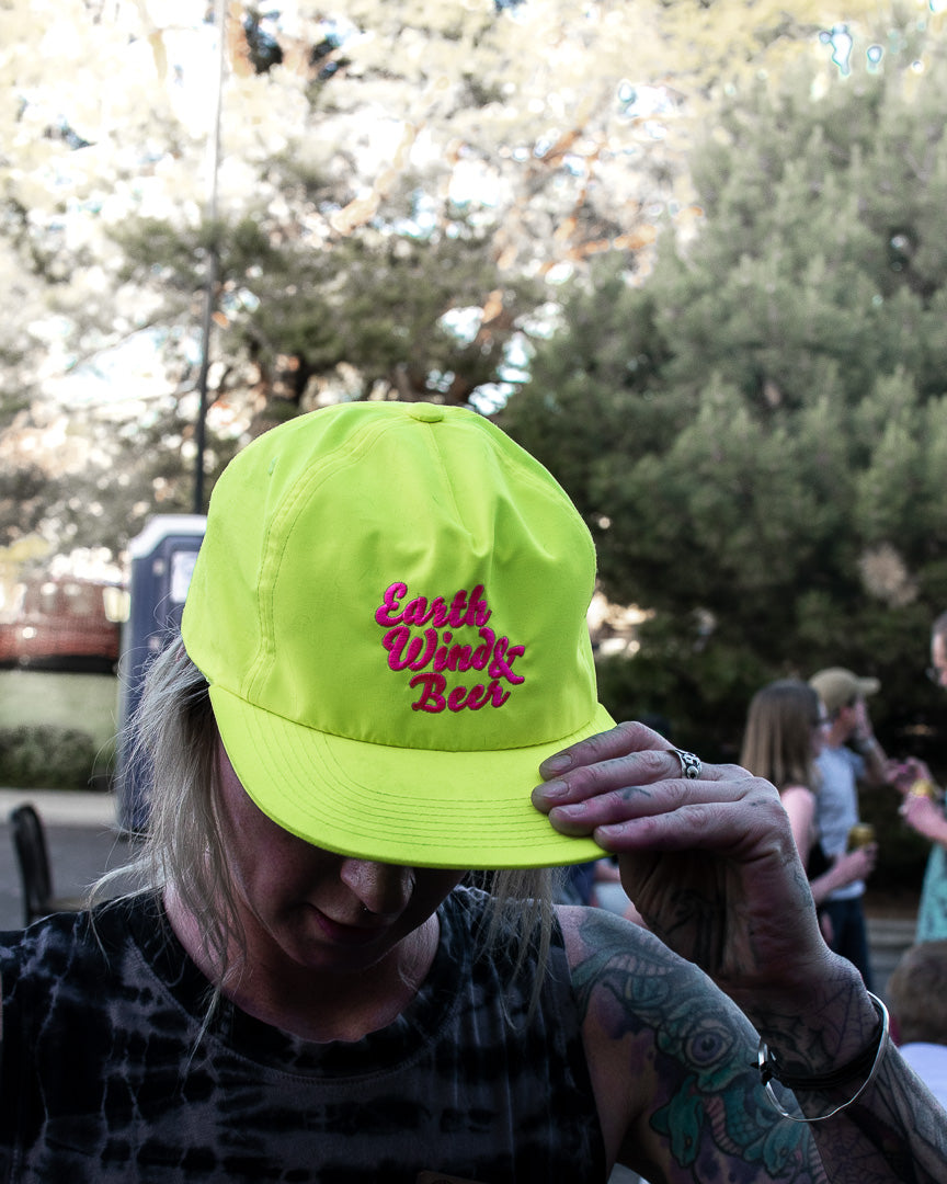 A woman grabs the brim of a neon hat